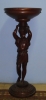 Coluna para floreira em madeira estilo Renascença, suportada por figura de menino entalhada. Base redonda guarnecida com ramos. Alt.: 89cm.