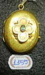 Antigo guarda lembrança em ouro 18k decorado com flor, tendo ao centro esmeralda. Peso: 4,4g.
