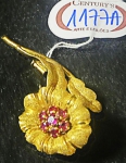 Broche em feitio de ramo de flor em ouro 18K, núcleo com 7 pedras vermelhas, provavelmente rubis.Peso: 11,3g.