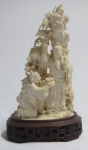 Grupo escultórico em marfim representando "Dignatário e serviçal junto aos rochedos". Base em madeira com entalhes vazados. Alt.: 21cm. China - séc. XIX/XX.