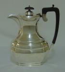 Tea pot em prata inglesa período "George V", contraste da cidade de "Sheffield" de 1930. Corpo ovalado com extremidades facetadas. Pega e puxador da tampa em madeira trabalhada. Alt.: 23cm. Peso: 690g. Marca de prateiro.