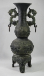 Raríssimo vaso arqueológico milenar chinês denominado "Hou" (utilizado em cerimoniais), em bronze patinado, lavrado com diagramas diversos. Base tripóide. Laterais guarnecidas com "animal híbrido e argola". Apresenta inscrições na parte superior. Alt.: 37,5cm.