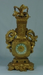 Antigo relógio provavelmente americano com caixa em metal dourado, adornado com "dragões celestiais e vegetação oriental" no padrão "chinoiserie". Mostrador esmaltado. Alt.: 22cm. Funcionando.