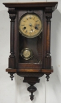 Relógio de parede da marca "2 Setas". Caixa em madeira clara com entalhes e torneados no estilo "capelinha". Alt.: 55cm. Alemanha - 1900. Funcionando.