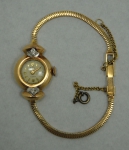 Relógio feminino suíço de pulso da marca "Adir" (década de 40/50). Caixa e pulseira em ouro 18k - 750mls contrastado. Laterais guarnecidas com 2 brilhantes. Peso: 13,7g. Movimento a corda. Funcionando.