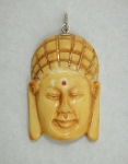 SILVIO BRETAS. Pendente esculpido em marfim representando "Cabeça de Buddah" guarnecida em ouro 18k e rubelita. Medida: 5,5 X 4. Sem assinatura.