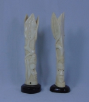 Par de solifleurs esculpidos em marfim africano, lavrados com cabeças de guerreiros, folhagens e serpentes. Base em madeira. Alt.: 23cm.