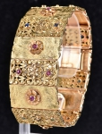 Magnífica pulseira oriental filigranada e vazada em ouro 18k contrastado, com ornamentação floral, rubis, safiras e esmeraldas. Peso: 64,2g.