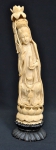 Escultura em marfim representando "Divindade Kuan Yin com frasco de perfume, ramo de tulipas sobre flor de lótus". Base em madeira trabalhada. Alt.: 37cm. China - 1900. (Flor de lótus da cabeça com pequenos colados).