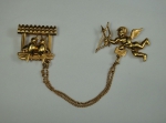 Dois antigos broches em ouro 14k unidos com pulseira representando "cupido com arco e flecha e pequena casinha com casal de passarinhos". Alt. do cupido: 3,0cm.