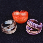 Três anéis em vidro moldado de Murano nas cores coral, violeta e branco salpicados com pó de ouro. Aros: 20, 18 e 16.