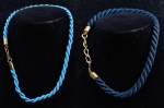 Par de gargantilhas torsades em fio de seda, nas cores azul safira e azul turquesa. Guarnição em ouro baixo. Comp.: 37,5cm e 43cm.