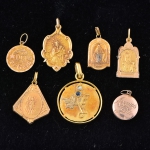 Sete medalhas sacras diversas, sendo uma com ramos de flores, 1 safira e 1 brilhante. Peso: 7,8g.