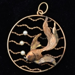 Antigo pendente circular vazado em ouro 18k no feitio de "peixe no aquário" guarnecido com 3 pérolas. Diam.: 3,3cm. Peso: 5g.