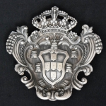 Escudo Coroado em prata portuguesa contraste "Javali-Porto", com trabalhos, lavrados, repuxados e cinzelados. Medida: 15 X 14. Peso: 290g. Prateiro "Alves - Porto".