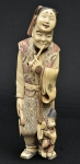 Okimono em marfim policromado representando "Adestrador de macaco com máscara". Alt.: 23cm. Japão - 1900.