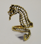 Curioso anel no feitio de "cavalo marinho" em ouro 18k com finos trabalhos vazados. Olho com brilhante. Aro: 8. Alt.: 6,4cm. Peso: 6,6g.