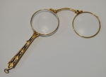 Antigo pince-nez em ouro 14k contrastado, decorado com finos raminhos e esmalte azul. Comp.: 10,5cm. Peso bruto: 27,4g.
