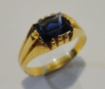 Anel unissex em ouro 18k com pedra azul, provavelmente safira. Aro: 26. Peso: 5,1g.