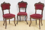 Três cadeiras em madeira clara com ricos entalhes no estilo "Barroco-Rococó". Assento e encosto forrados em veludo vinho.