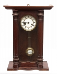 Relógio alemão de parede provavelmente da marca "Junghans" (circa 1890). Caixa em madeira guarnecida nas extremidades com meias colunetas torneadas. Mostrador esmaltado. Alt.: 57cm.