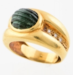 Anel em ouro 18k com pedra verde cabochon canelada provavelmente turmalina e 6 brilhantes laterais. Aro: 16. Peso: 7,7g.