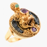 Antigo anel em ouro baixo esmaltado, guarnecido com pedras vermelhas e verde, provavelmente rubis e esmeralda. Aro: 14/15. Peso: 6,4g.