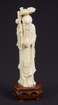 Figura esculpida em marfim, representado "Sábio com cajado e pêssegos". Base em madeira. Alt.: 21cm. China - 1900.