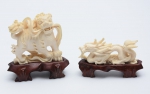 Duas figuras esculpidas em marfim, representando "Cão de Fó" e "Dragão". Base em madeira. Alt.: 9cm e 5cm. China-1900. Reproduzido com foto no catálogo.