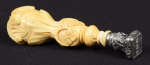 Sinete em marfim europeu do séc. XIX, esculpido com conchas, rosetas e volutas. Timbre monogramado em prata trabalhada no mesmo estilo do marfim. Alt.: 10cm.