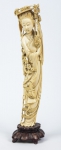 Figura esculpida em marfim, representado "Divindade Kuan Yin com cesta de flores e borboletas". Base em madeira. Alt.: 33cm. China - 1900.