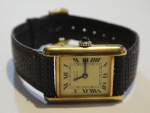 CARTIER. Relógio feminino suíço de pulso da marca "Cartier". Caixa em plaque d'or. Coroa em safira cabochon. Pulseira original em couro. Medida da caixa: 2,7 X 2,0. Movimento a corda. Funcionando.
