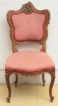 Cadeira em madeira clara, entalhada no estilo barroco rococó, ornamentada com florões, rocalhas e volutas. Assento e encosto forrados em tecido rosa floral. (Pequeno lascado no entalhe superior).