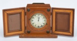 Relógio americano com despertador da marca "Westclox". Caixa em madeira com 2 placas laterais articuladas para porta retrato. Alt.: 23cm. Comp.: 50cm. (No estado).