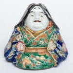 "Menina sentada" em porcelana japonesa "Imari", ornamentada com decoração floral com predominância ruge de fer. Alt.: 18cm. (Em função da fragilidade, este lote só poderá ser enviado para fora do estado através de transportadora especializada).
