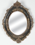 Espelho oval em cristal bisotado com guarnição revestida em pátina negra e entalhes florais dourados. Medida: 56 x 41. (Em função da fragilidade, este lote só poderá ser enviado para fora do estado através de transportadora especializada).