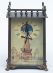Relógio em metal patinado, esmaltado com personagens mitológicos. Mostrador com moinho e fase de lua. Parte superior com cercadura vazada. Alt.: 15 cm. (Funcionando).