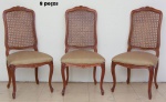 Oito cadeiras em madeira clara, estilo "Luis XV". Espaldar ondulado e entalhado com flores. Pernas arqueadas e pés de cachimbo. Encosto forrado em palhinha e assento forrado em tecido dourado.