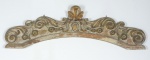 Ornamento arqueado entalhado com florões em cedro patinado e realçado a ouro. Brasil -séc. XVIII. Medida: 133 X 29. (Florão central superior colado).