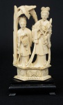 Grupo esculpido em marfim, representando "2 damas com cesto e peônias sob palmeira". base em madeira. Alt.: 19cm. China - 1900.