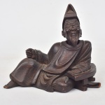 Escultura chinesa em madeira, representando "Ancião em repouso". Cabeça removível no formato de rolha. Alt.: 17cm. Comp.: 18cm. China - séc. XIX.