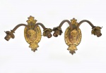 Par de apliques para 2 luzes em bronze patinado, estilo "Luis XV". Estrutura oval arrematada com florões. Braços arqueados. Alt.: 30cm.