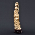 Figura esculpida em marfim, representando "Imortal com Cajado, pêssegos e cabaça". Base em madeira trabalhada. Alt.: 34cm. (Ornamento sobre a cabeça colado).