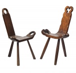 Duas cadeiras em madeira clara estilo rústico. Espaldar inclinado. Assento arqueado com extremidades vazadas. Estrutura tripoide. Alt.: 87cm e 84cm. Comp.: 50cm e 56cm.