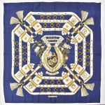 HERMÉS - PARIS. Versátil lenço francês em seda estampada nas cores azul e dourado, da famosa marca "Hermés". Medida: 90 x 90.