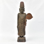 TAILÂNDIA - 1900. "Divindade Budista com Estandarte", escultura em madeira patinada, marchetada com madrepérolas. Alt.: 93cm.