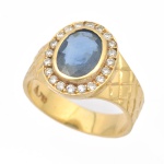 Antigo anel em ouro 18k - 750mls contrastado com pedra azul central provavelmente safira, emoldurada com 21 diamantes. Aro: 21. Peso: 8,9g. Marca de grife.