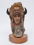NEIL J. ROSE (E.U.A. - SÉC. XX). "Cabeça de Chefe Apache", escultura em madeira policromada. Base oval também em madeira. Alt.: 34cm. Assinada.