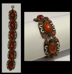 Antiga pulseira em metal dourado e filigranado, decorada com pedras vermelhas cabochon e esmalte. Comp.: 18cm.