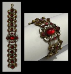 Antiga pulseira em metal dourado e filigranado, decorada com pedras vermelhas cabochon e esmalte. Comp.: 18cm.